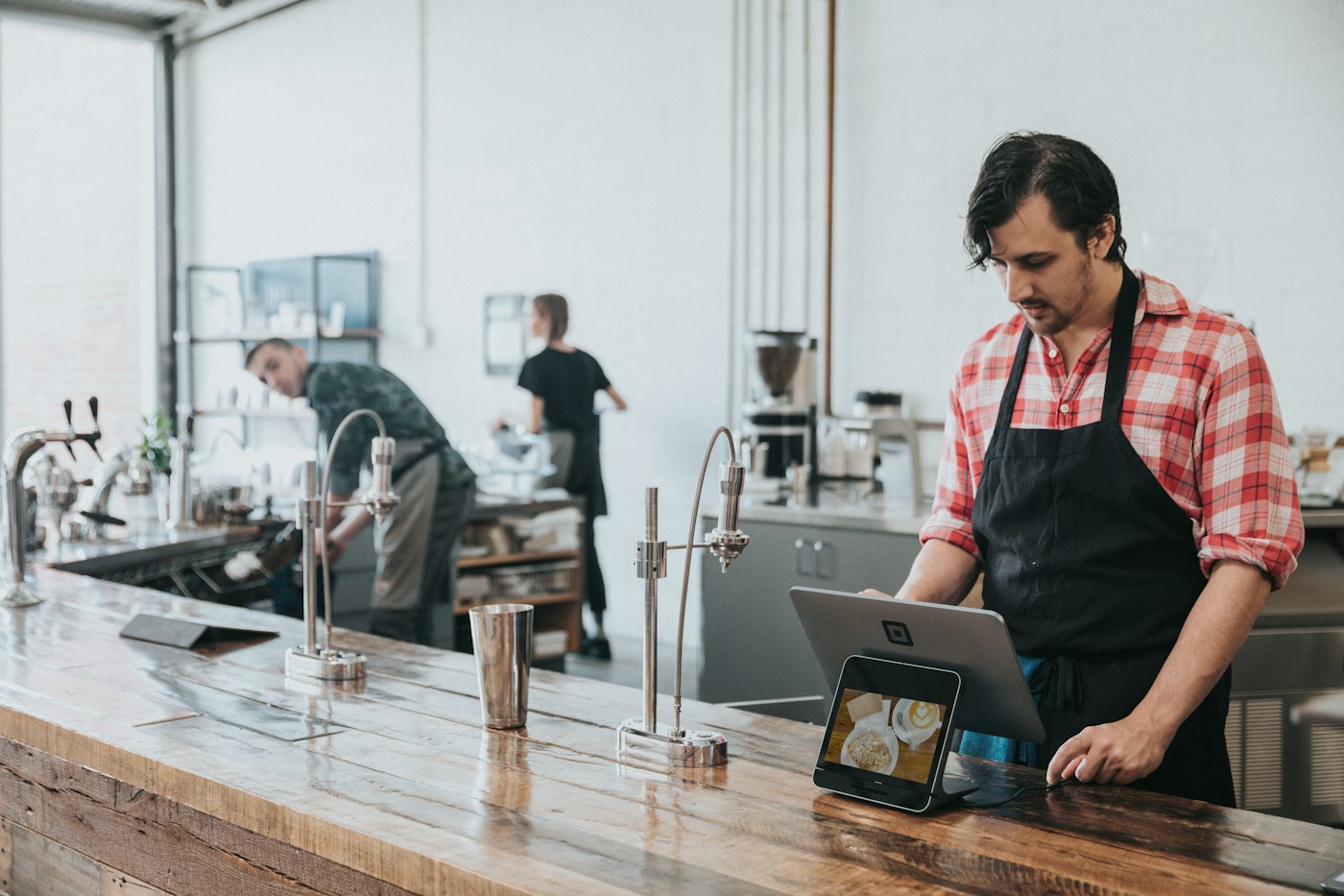 Barista reviewing the day's orders on a tablet at the counter