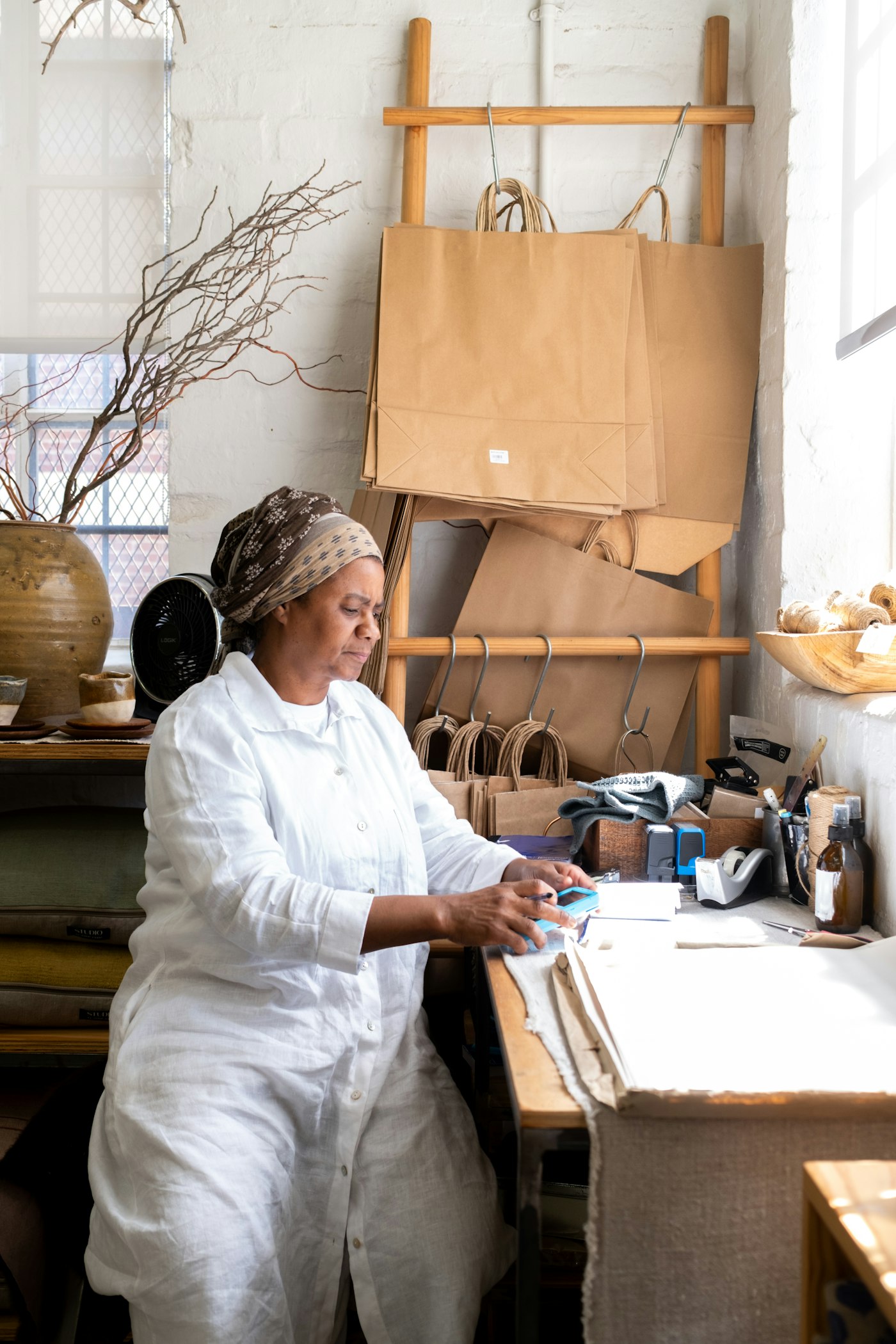 Shop owner at her workbench surrounded by craft supplies