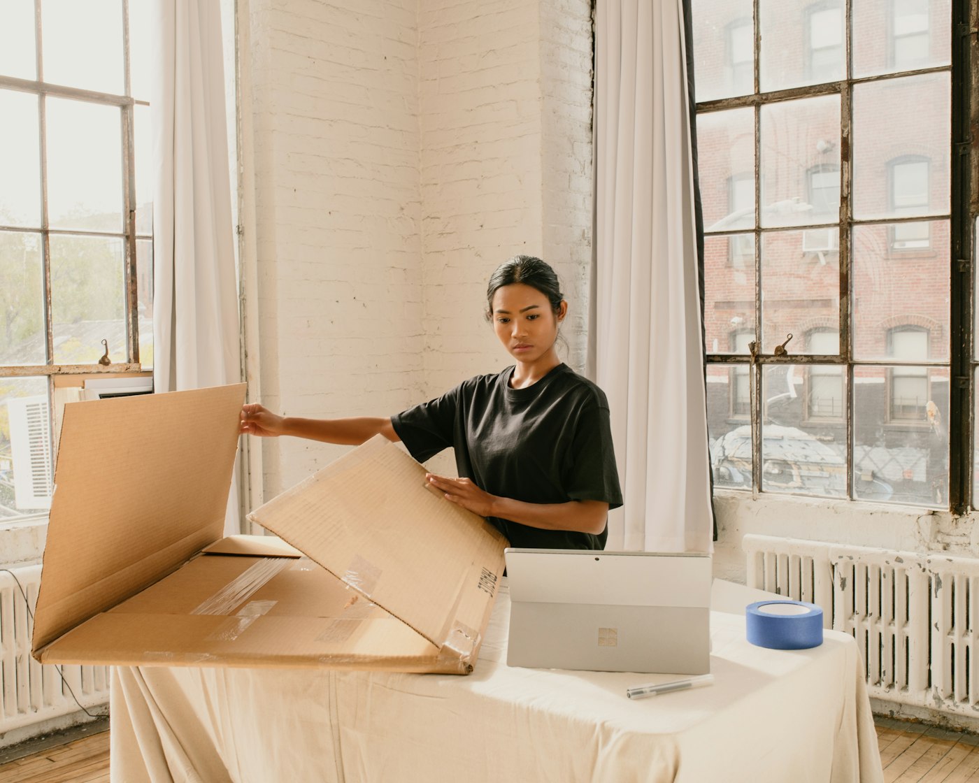 Founder packing an order next to stacked cardboard boxes
